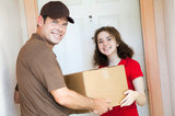 Happy customer receiving a package from a delivery man.  Focus on girl.  