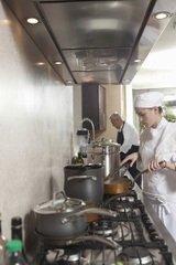 Side view of male and female chefs working in commercial kitchen