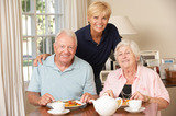 Senior Couple Enjoying Meal Together At Home With Home Help