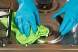 Closeup horizontal image of hands wearing rubber gloves while removing soap from stove top range green with microfiber rag<br />
<br />
 Cleaning Services Toronto Pro 1075 Bay Street #102A 
