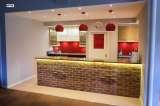 After - Wokingham Theatre. Oak effect units with Silestone worktop and red splash back.