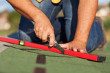 Worker installing bitumen roof shingles - closeup on hands