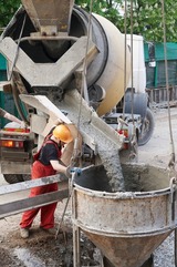 worker builder controlling concrete filling process at construction site