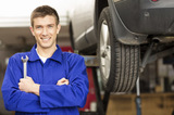 Portrait of a happy young car mechanic holding wrench with car on hoist in background. Horizontal shot., Lake Shore Honda, Etobicoke
