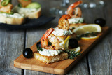 Appetizer canape with shrimp and olives on cutting board on table close up