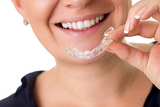 Woman with perfect teeth holding invisible braces, correction teeth braces for night