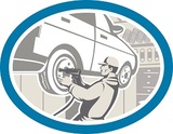 Illustration of an automotive mechanic changing repairing automobile car vehicle tire in workshop garage set inside oval shape done in retro style.