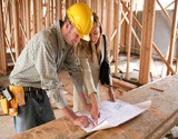 A home designer working with a home buildering and inspecting the blueprints
