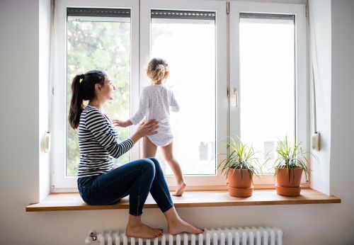 Beautiful young mother sitting on window sill with her cute little daughter looking out of window Profile Photos of Sunstopper Window Tinting 2544 South Harbor City Boulevard - Photo 9 of 11