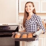 Pretty young woman taking an oven-tray with baked bread from oven, Berkeley Appliance Repair Works, Berkeley