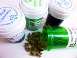Close-up of four medical marijuana prescription containers. One opened container is in the foreground with cannabis bud falling out. Rx Depot 180 Talmadge Road Suite, #598 