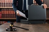 50245697 - midsection of lawyer putting documents in briefcase with gavel at desk in courtroom