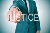 27500695 - man wearing a suit pointing the finger to the word justice written in the foreground