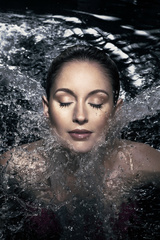 Caucasian woman in her 20's with eyes closed submerged to her neck in water